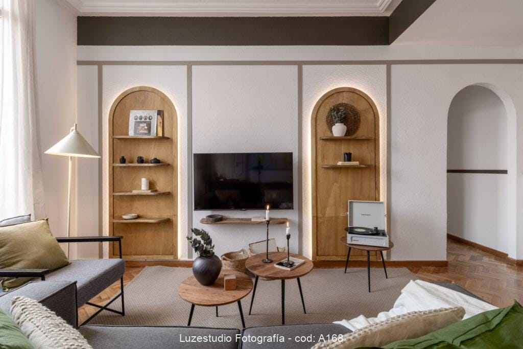 interior de sala de estar con mesitas redondas y pared con formas circulares de madera y estanterías con decoración en vivienda fotografiada por fotógrafo de interiores en oviedo